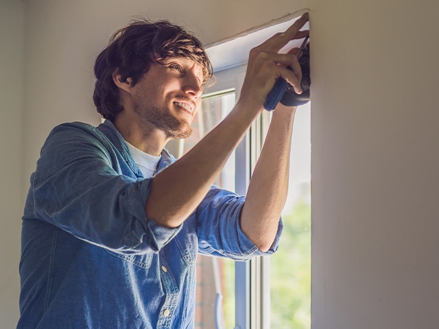 A man measuring a window frame.